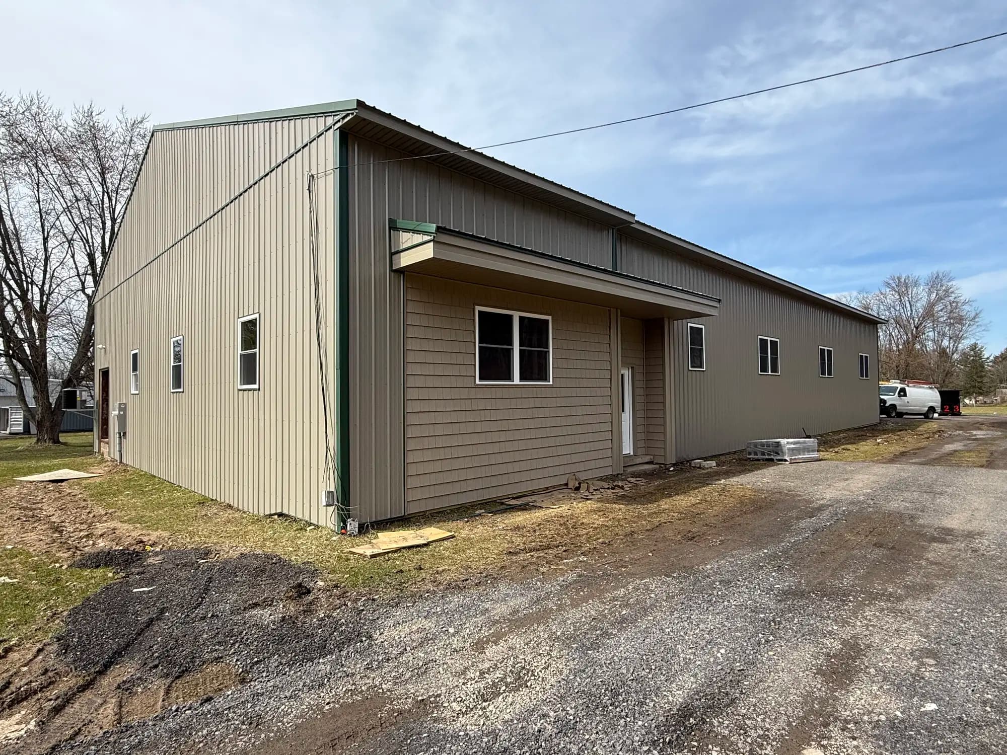 Tan and green barndominium with residential-style entrance and vinyl siding